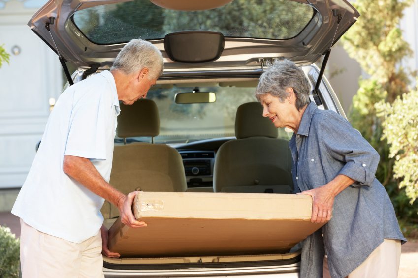 Senior Couple Loading Large Package Into Back Of Car