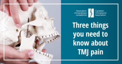 Human skull model with person pointing to TMJ