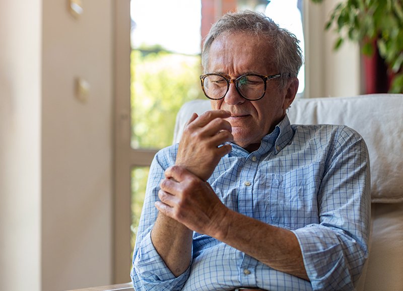 Elder man holding his wrist with discomfort