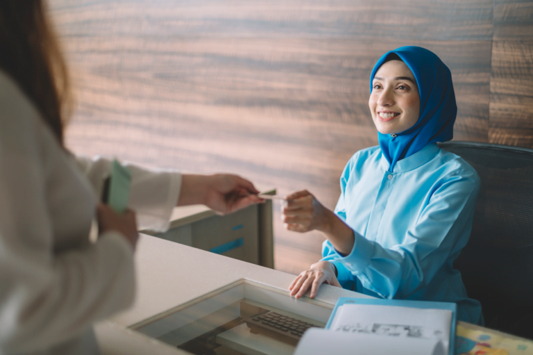 Patient passing her payment information to a clinic receptionist