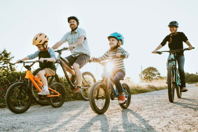 A father and mother ride mountain bikes together with their two small children.