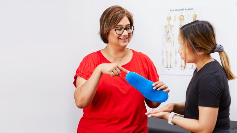 Female chiropractor talking about the importance of orthotic insoles to a female client