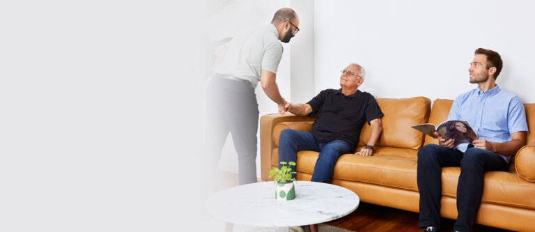 Male chiropractor greeting elderly patient in waiting room