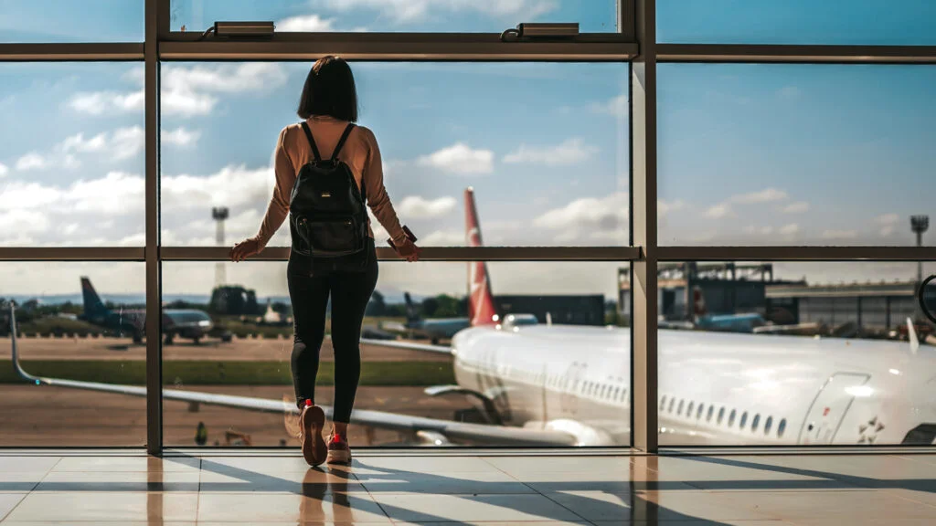Femme à l'aéroport regardant par la fenêtre