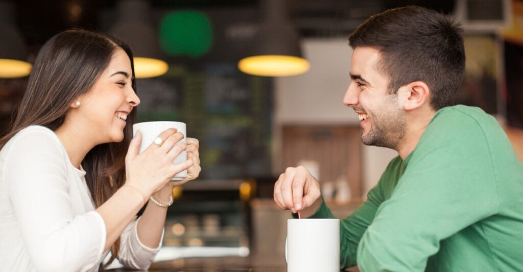 A couple laughs while drinking coffee. (Photo: Antonio_Diaz / Unsplash)