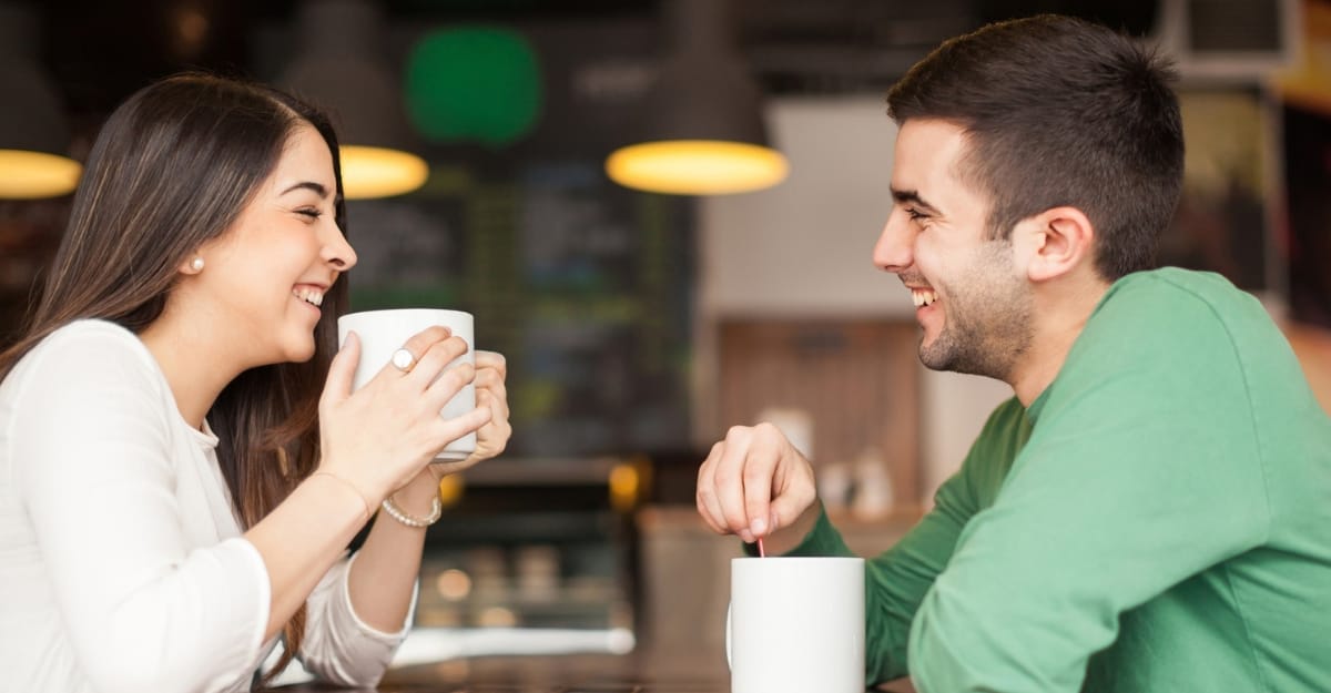 A couple laughs while drinking coffee. (Photo: Antonio_Diaz / Unsplash)