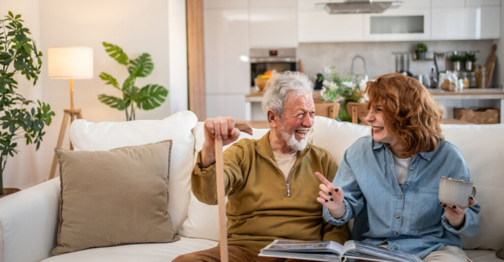 A man and a woman laugh while looking through a photo album. (Photo: Milan Markovic / iStock)