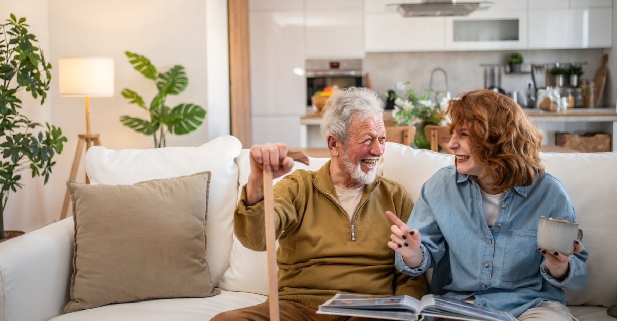 A man and a woman laugh while looking through a photo album. (Photo: Milan Markovic / iStock)